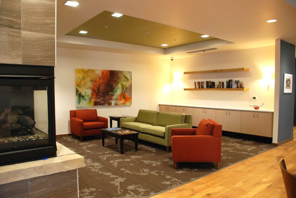 A modern living room with colorful sofas, artwork, and stylish shelving.