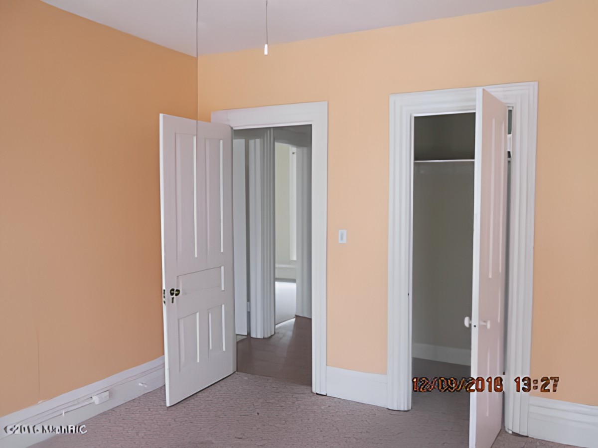 An interior room with orange walls, featuring open doors and a closet.