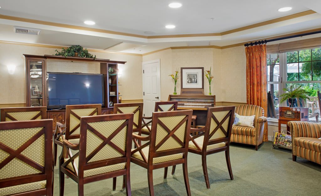 A conference room with neatly arranged chairs facing a television and seating area.