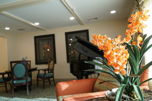 A cozy interior space featuring a piano, elegant chairs, and vibrant orange flowers.