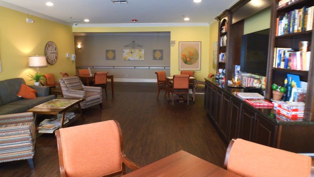 A cozy dining area with wooden floors, tables, and chairs under warm lighting.