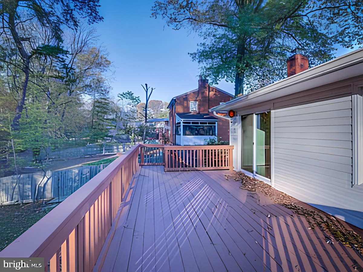A spacious outdoor deck attached to a house, surrounded by trees.