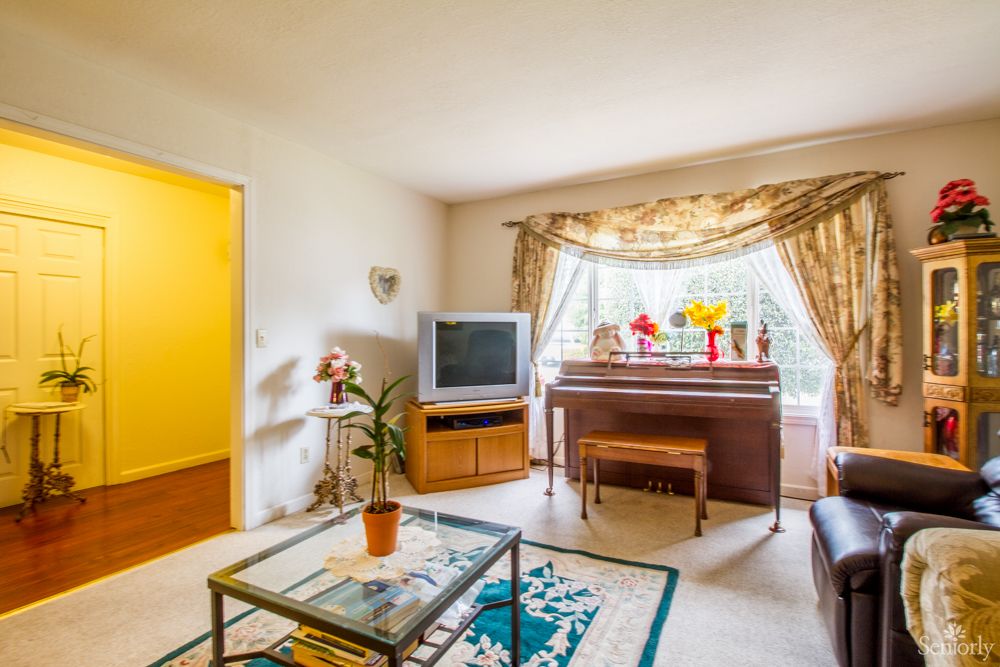 A cozy living room featuring a television and piano, accented with decorative items and curtains.