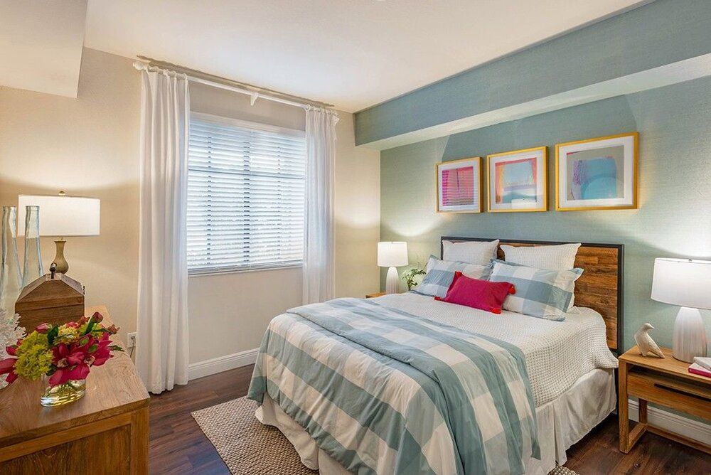 A cozy bedroom with striped bedding and colorful artwork above the headboard.