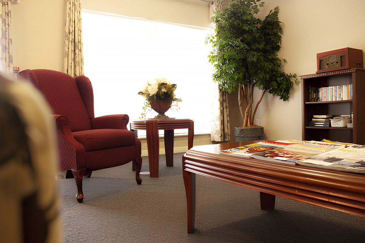 A cozy living room with a comfortable armchair, wooden tables, and elegant decor.