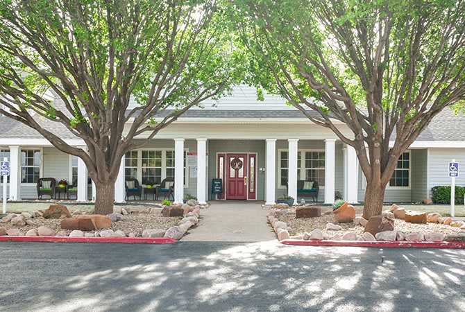 A building entrance with a welcoming front door and surrounding trees.