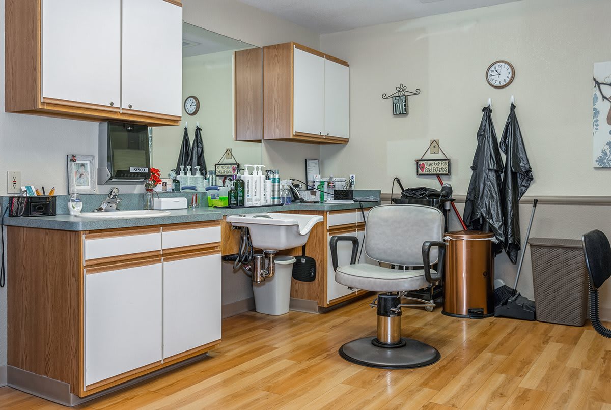 A cozy barbershop interior with a hair cutting chair and various salon equipment.