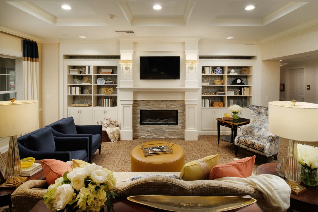 A cozy living room with a fireplace, surrounded by built-in shelves and comfortable seating.