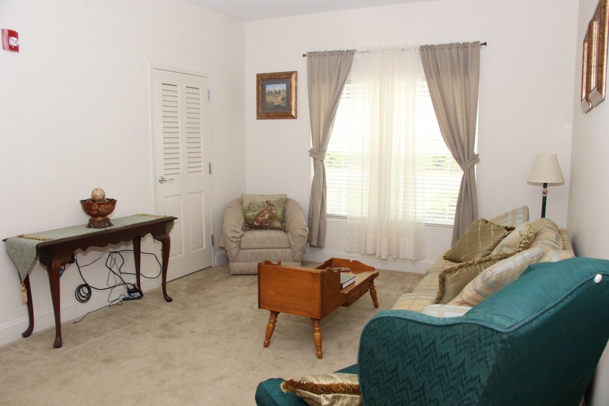 A cozy living room with a sofa, chair, and table near a window with curtains.