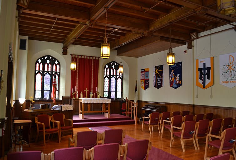 The interior of a chapel featuring an altar, wooden ceiling, and decorative banners.