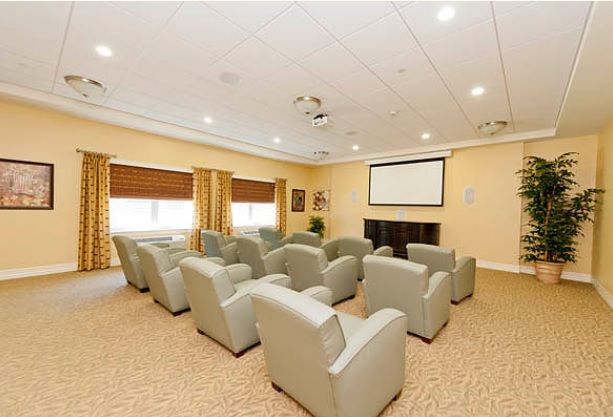 A cozy home theater room with rows of comfortable chairs and a large screen.
