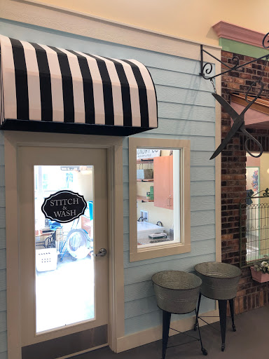 A charming storefront featuring a blue wall and a classic black and white striped awning.