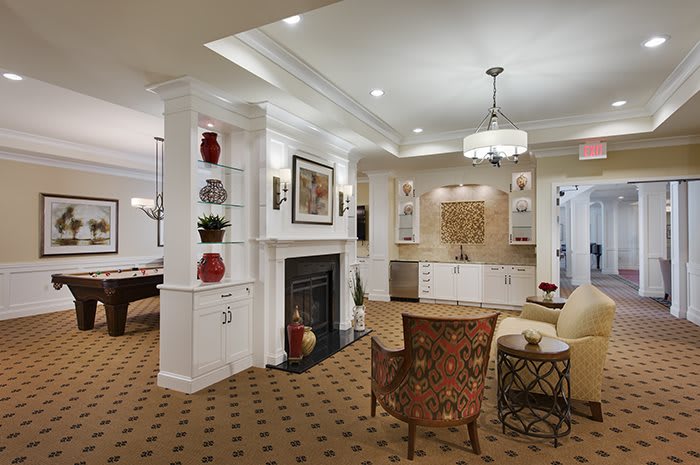 A cozy living room with elegant interior design featuring a fireplace, comfortable seating, and a chandelier.