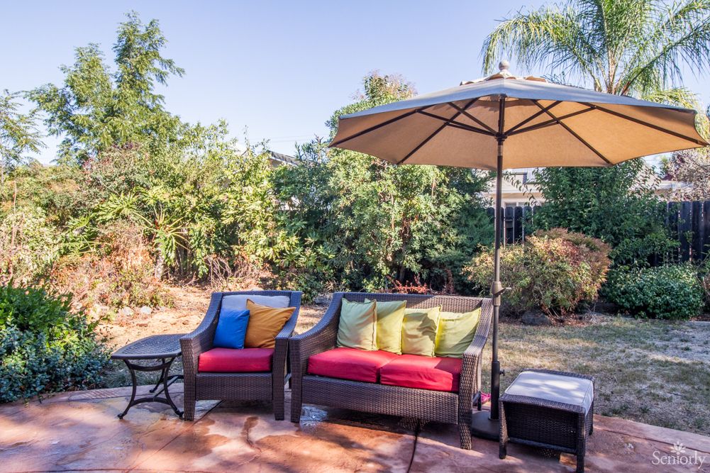 A cozy backyard patio with comfortable seating and a large umbrella on a sunny day.