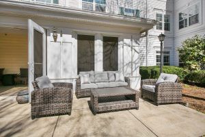 A cozy outdoor patio with wicker furniture and cushions.