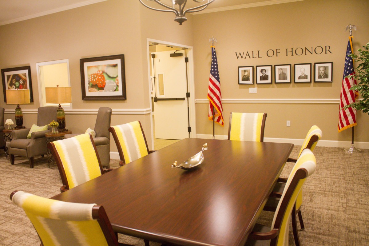 A conference room featuring a large table, chairs, an American flag, and a 'Wall of Honor'.