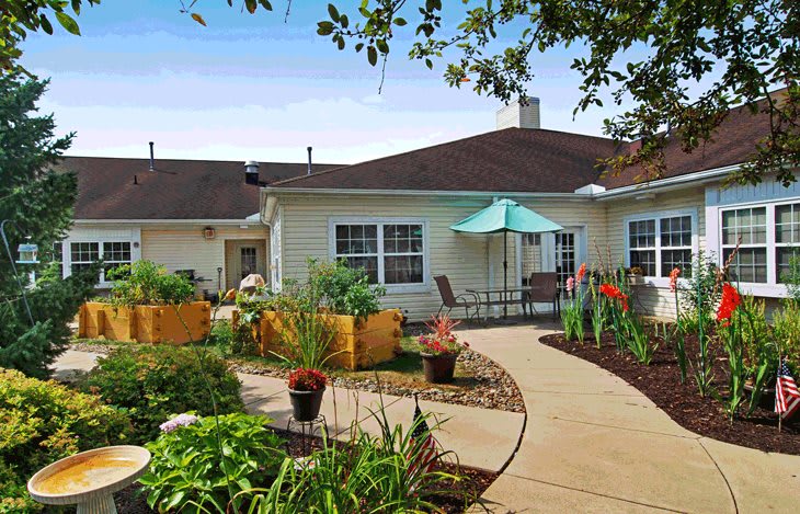 A well-maintained garden with a pathway leads to a cozy building patio.