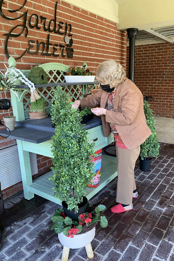 A woman tending to plants at a gardening station while wearing a mask.
