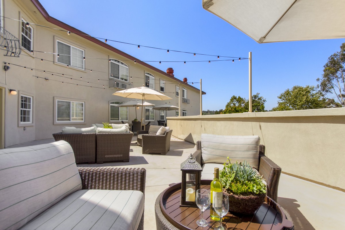 A cozy outdoor patio with comfortable seating and umbrellas on a sunny day, perfect for relaxation.