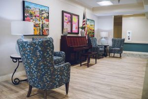 A cozy waiting room featuring comfortable chairs, a piano, and various artworks on the walls.