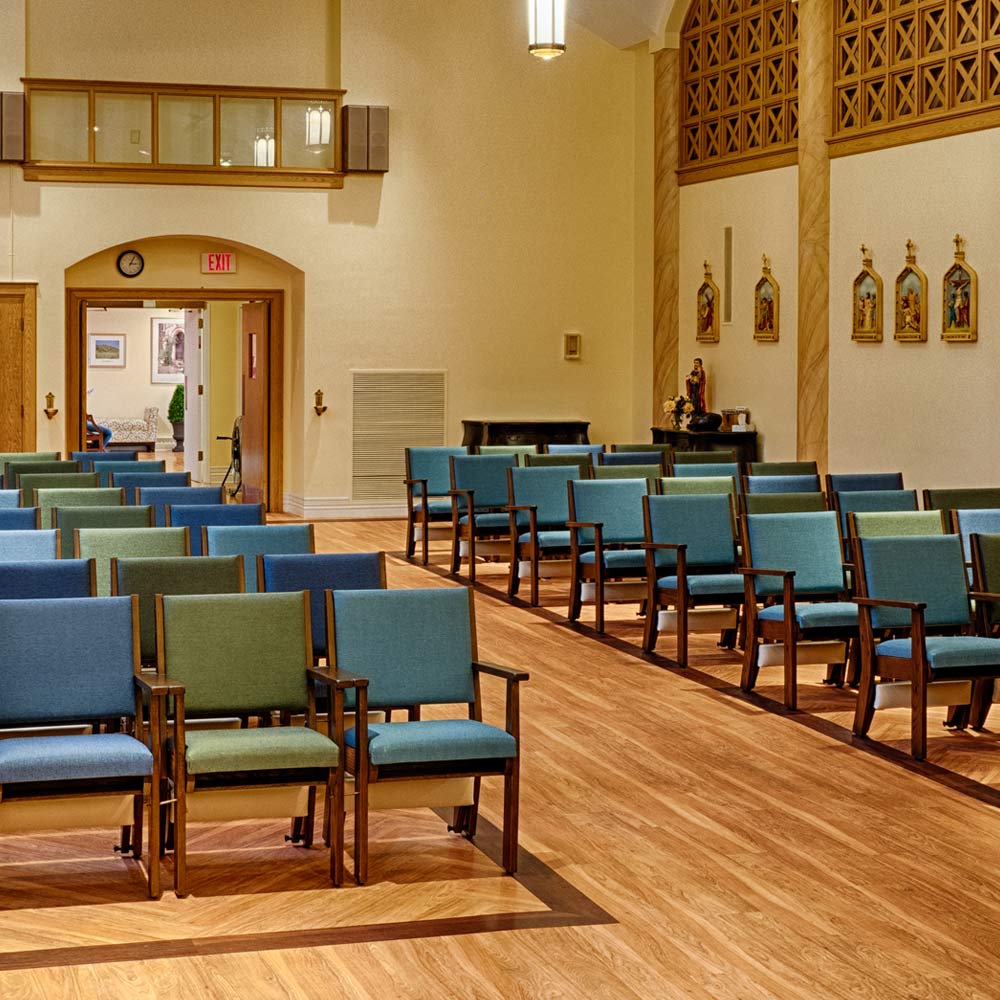 An interior view of a church with neatly arranged chairs and wooden flooring.