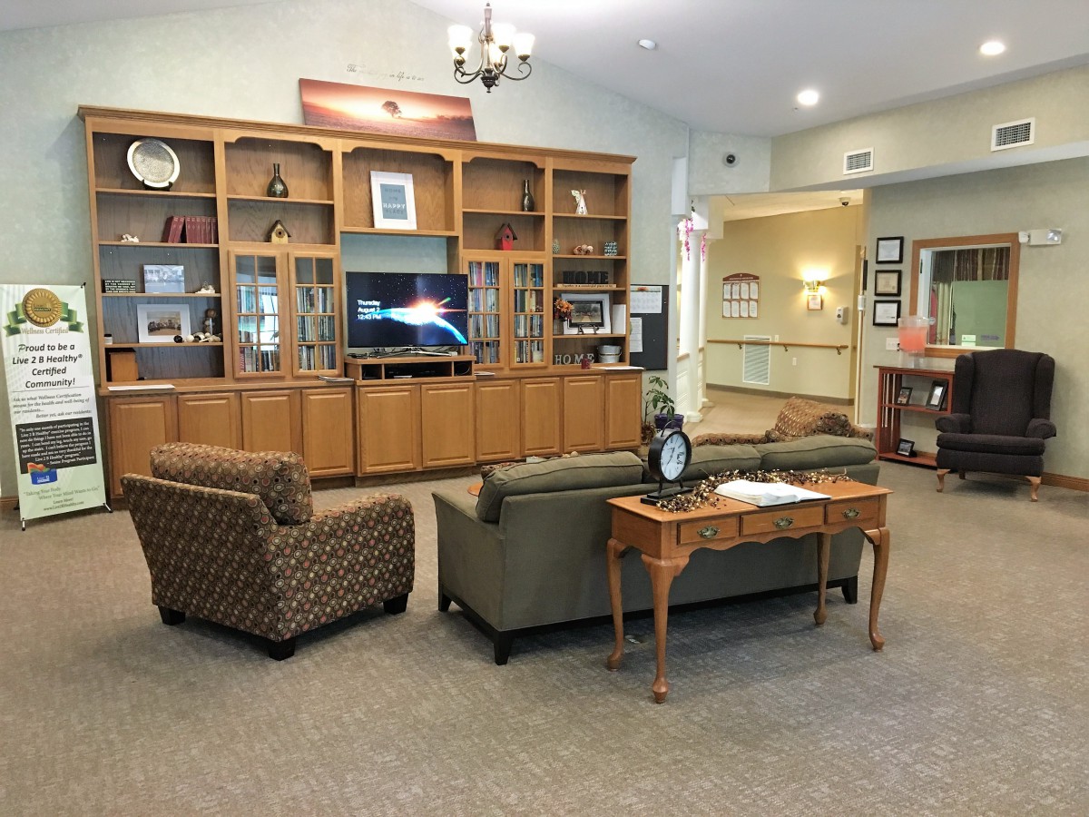 A cozy living room with a television, sofas, and decorative shelves.