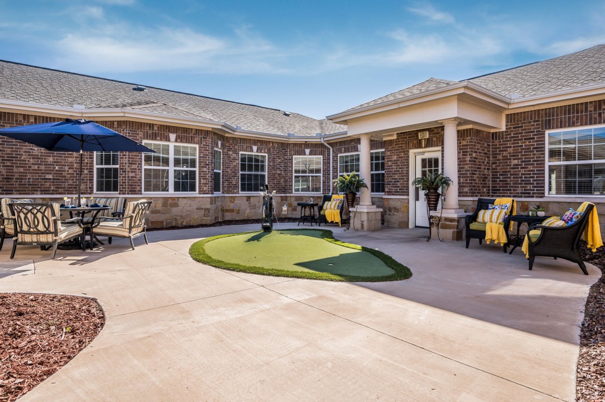 A well-maintained outdoor courtyard with a brick building, seating areas, and landscaping.