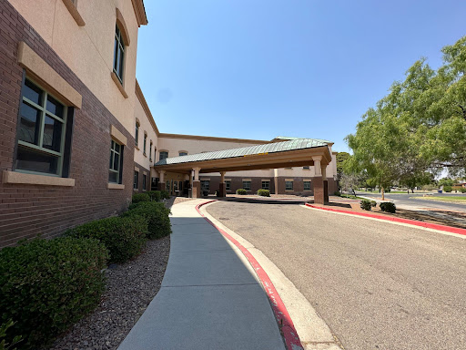 A view of the entrance to a building with a covered area and a well-maintained sidewalk.