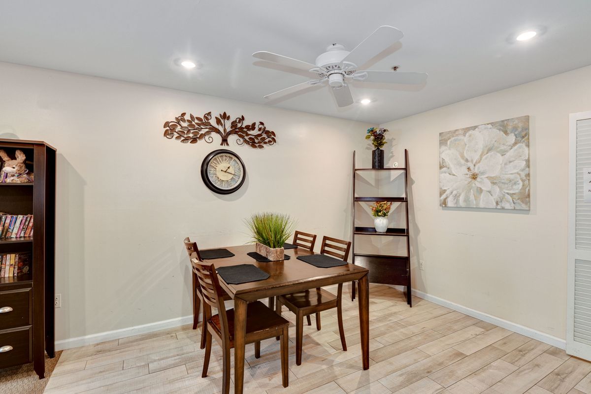 A cozy dining area featuring a wooden table set with chairs, decorative plants, and artwork on the walls.