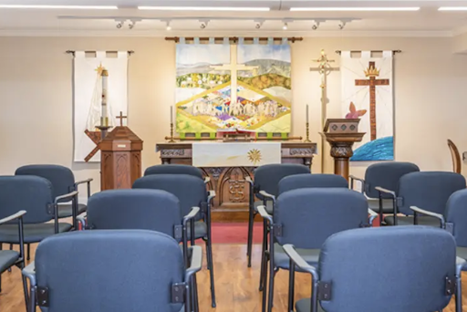 An interior view of a church, showcasing the altar and seating arrangement for attendees.