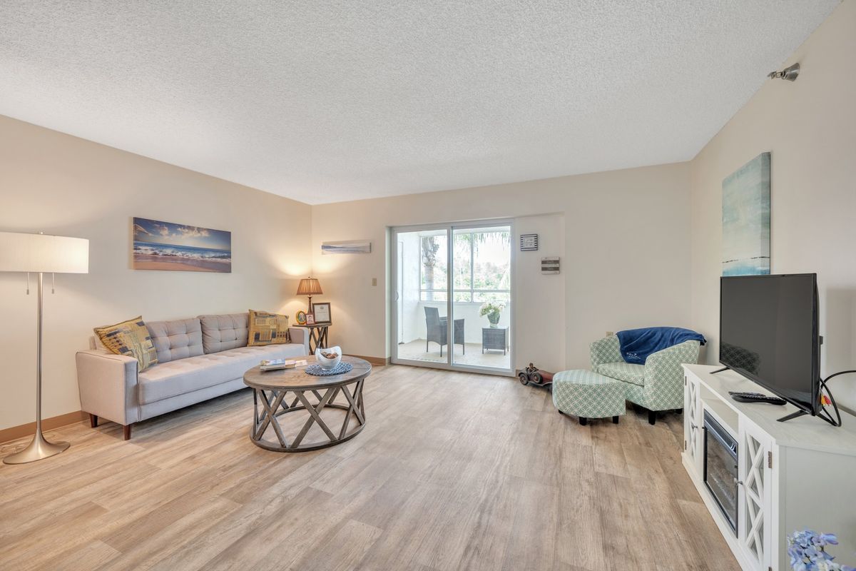 A cozy living room with a sofa, coffee table, and sliding glass door leading to a balcony.