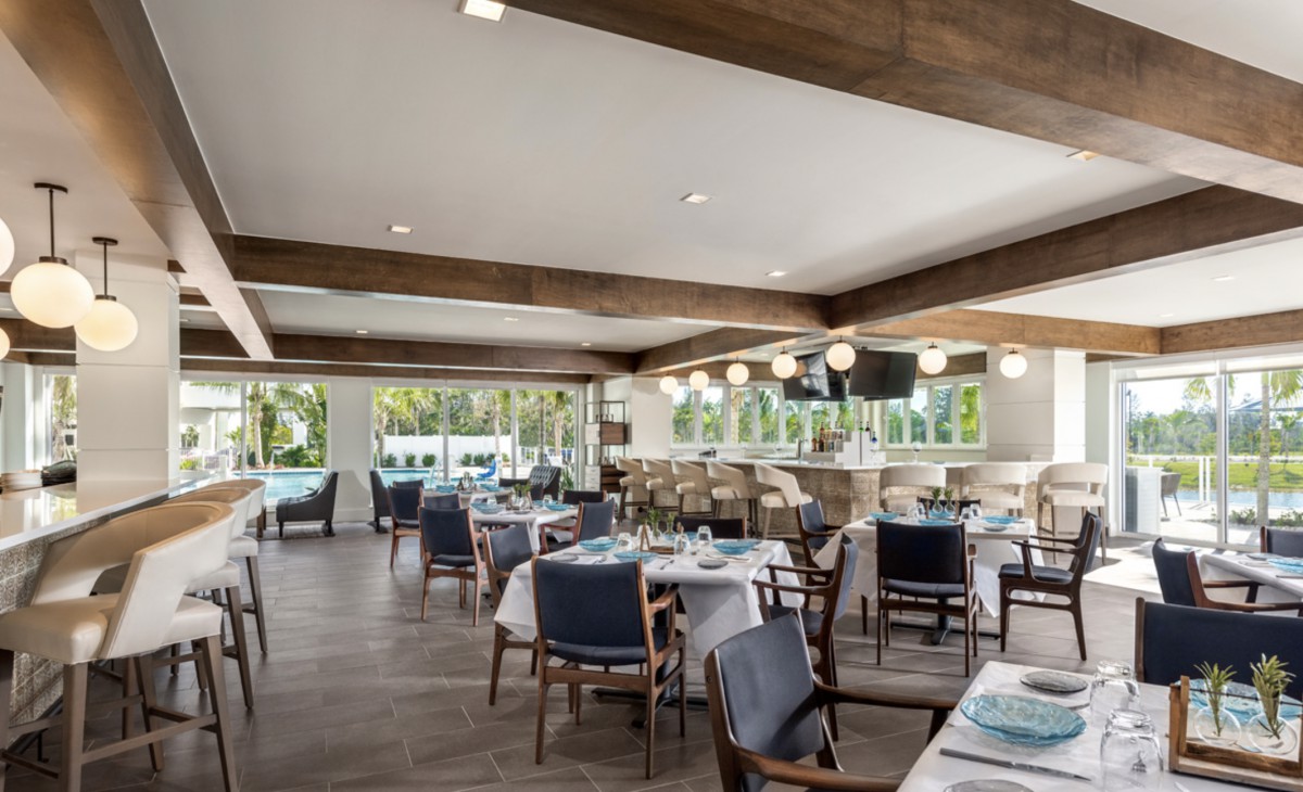 A modern restaurant interior with neatly arranged tables and wooden beams, featuring natural lighting.
