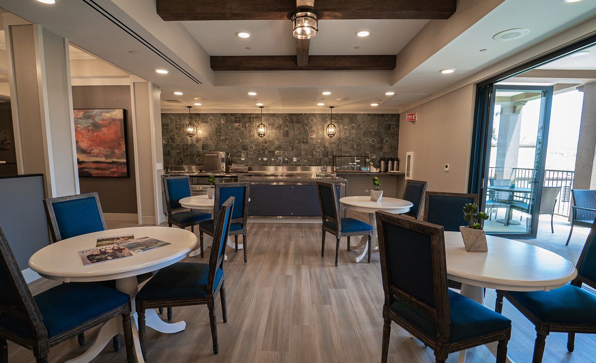 A modern dining area with stylish tables and chairs, featuring warm lighting and decor.