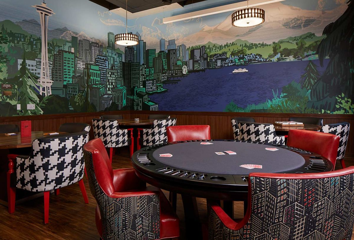 A stylish poker room featuring a mural of a cityscape, surrounded by red leather chairs and houndstooth-patterned seating.