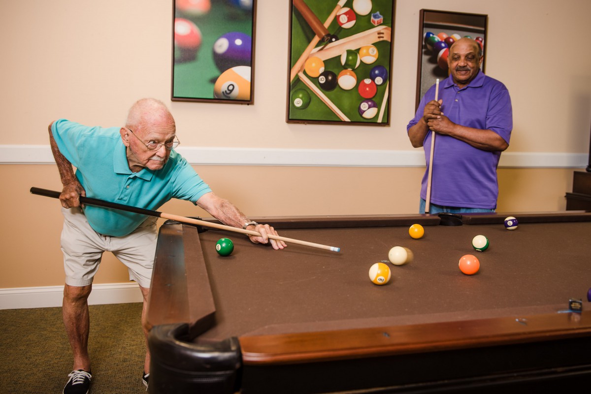 Two people enjoying a game of billiards indoors.