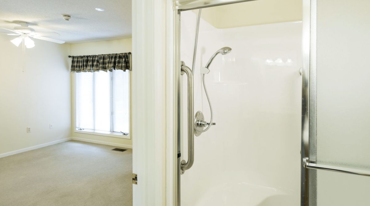 A view of a bathroom with an open shower door and white interior.