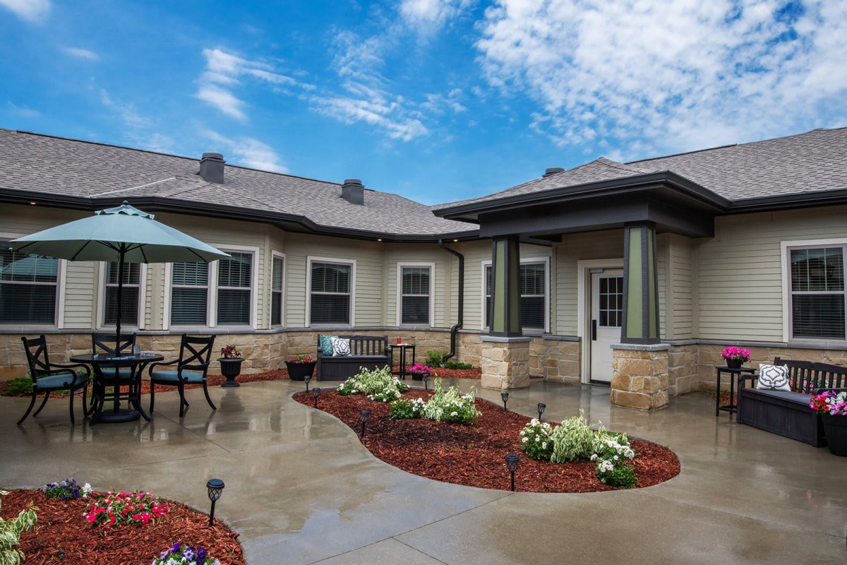 A well-maintained house with a landscaped patio and garden under a bright blue sky.