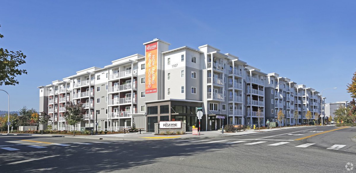A modern multi-story apartment building on a street corner.