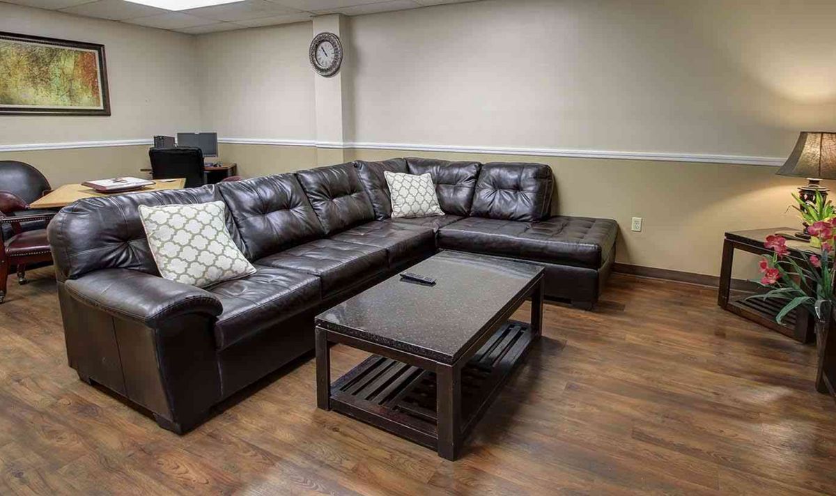 A cozy living room with a dark brown sectional sofa and a matching coffee table on wood flooring.