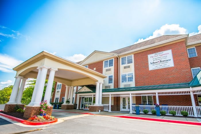 A hotel entrance with a covered driveway and columns under a clear blue sky.