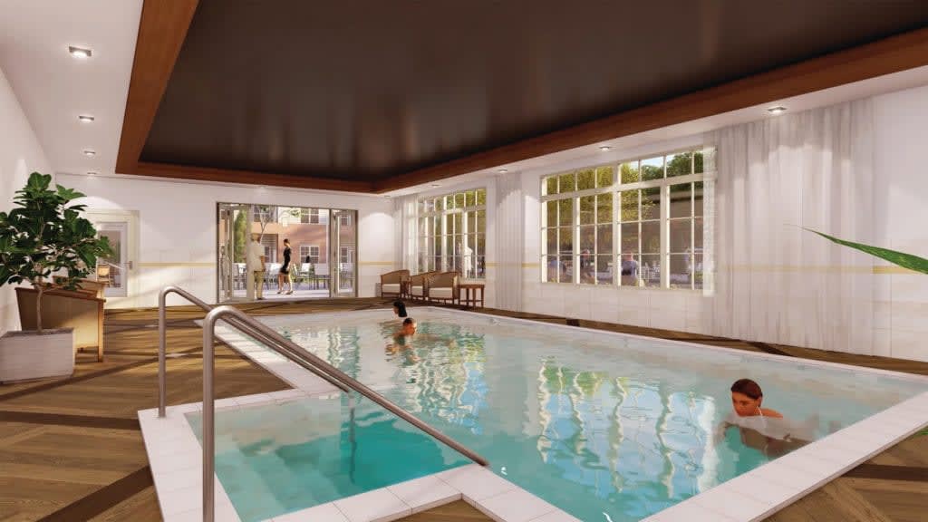 A person enjoying a swim in an indoor pool with large windows offering natural light.