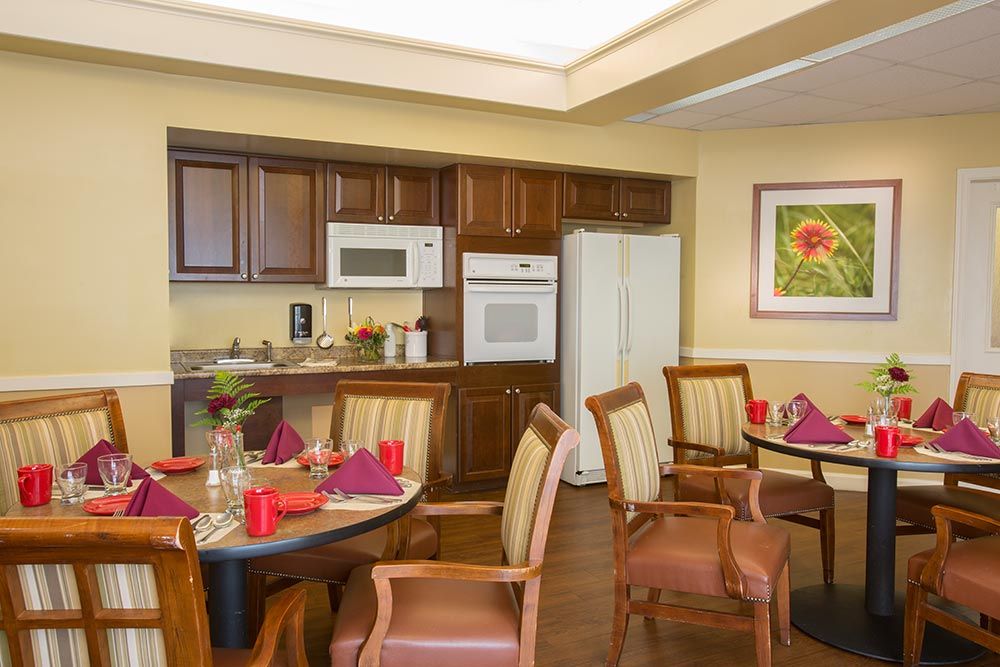 A cozy kitchen and dining area with wooden cabinetry, equipped with modern appliances and neatly set tables.