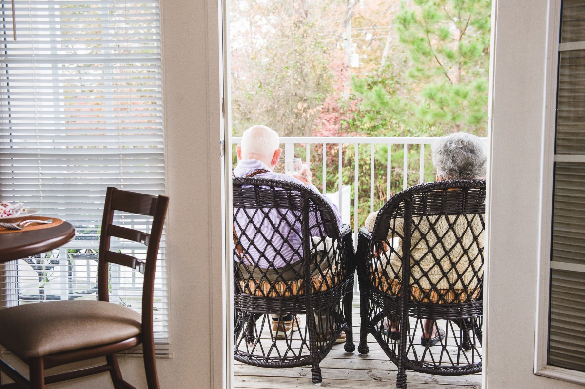 Two elderly individuals seated on a balcony, enjoying a peaceful moment together.
