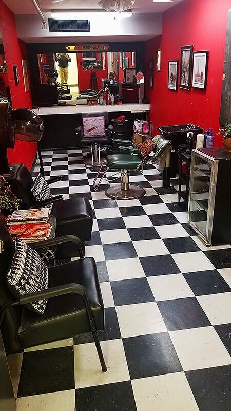 A stylish barbershop interior with checkered flooring and red walls.