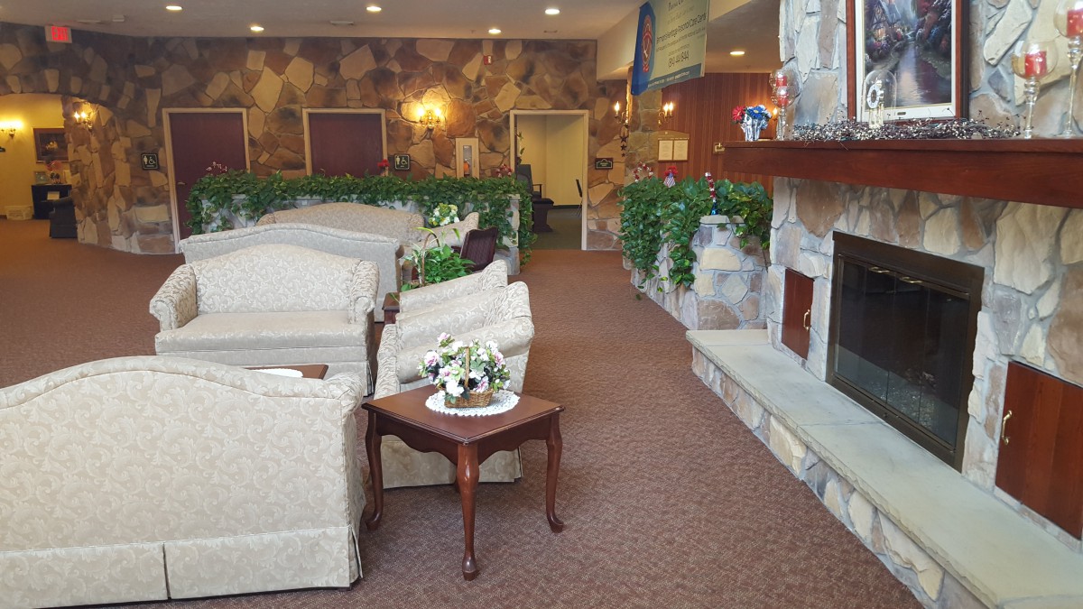 A cozy living room with sofas, a fireplace, and decorative plants.