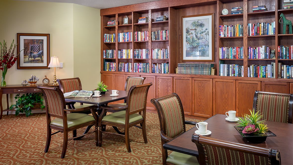 A cozy reading room with bookshelves, tables, and chairs.