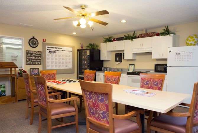 A well-organized meeting room featuring a long conference table with chairs and an adjacent kitchen area.