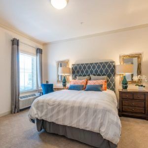 A well-decorated bedroom with a large bed, patterned headboard, and cozy furnishings.