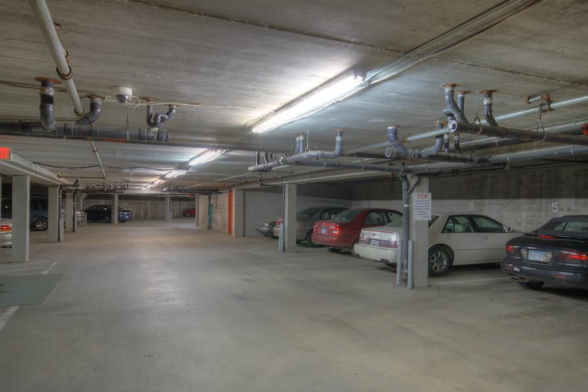 An indoor parking garage with several parked cars and overhead lighting.