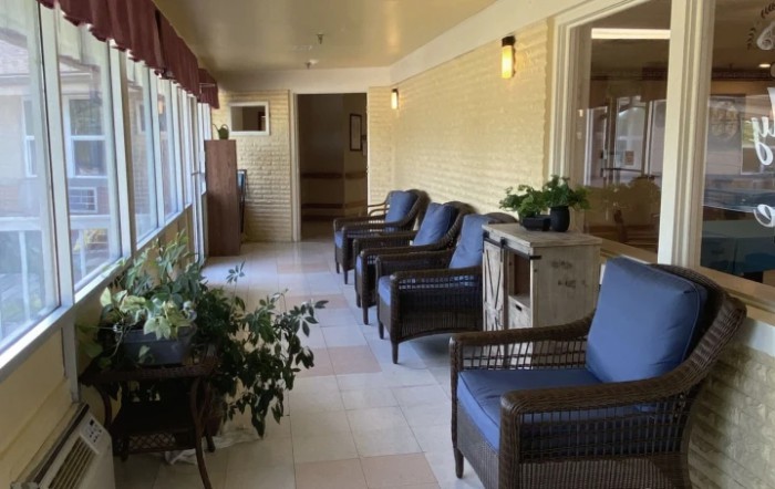 A cozy indoor seating area with chairs and potted plants along a hallway with large windows.